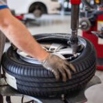 Garagiste fixant un pneu pour avoir la bonne pression de pneusur une jante dans un atelier mécanique