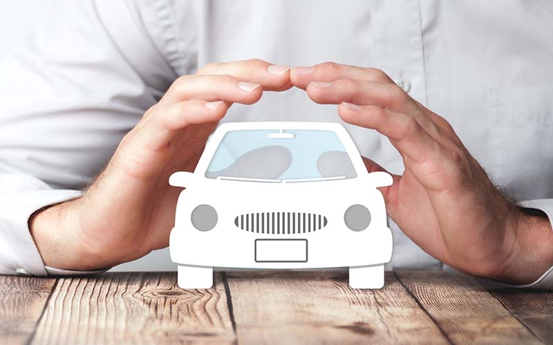 Protéger les mains sur l'icône de la voiture sur la table en bois - Concept d'assurance automobile