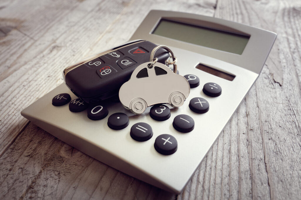 Porte-clés en forme de voiture et clé sur le concept de calculatrice pour les coûts d'automobile, les finances, l'assurance, l'entretien ou les factures de carburant