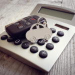 Porte-clés en forme de voiture et clé sur le concept de calculatrice pour les coûts d'automobile, les finances, l'assurance, l'entretien ou les factures de carburant