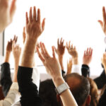 Grand public de personnes levant la main pour voter en faveur d'un sujet