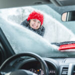 Jeune jolie femme nettoyant la voiture après le blizzard de tempête de neige