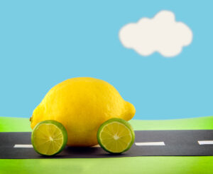 Une voiture de citron avec des roues de citron vert roulant le long d'une scène de papier de construction
